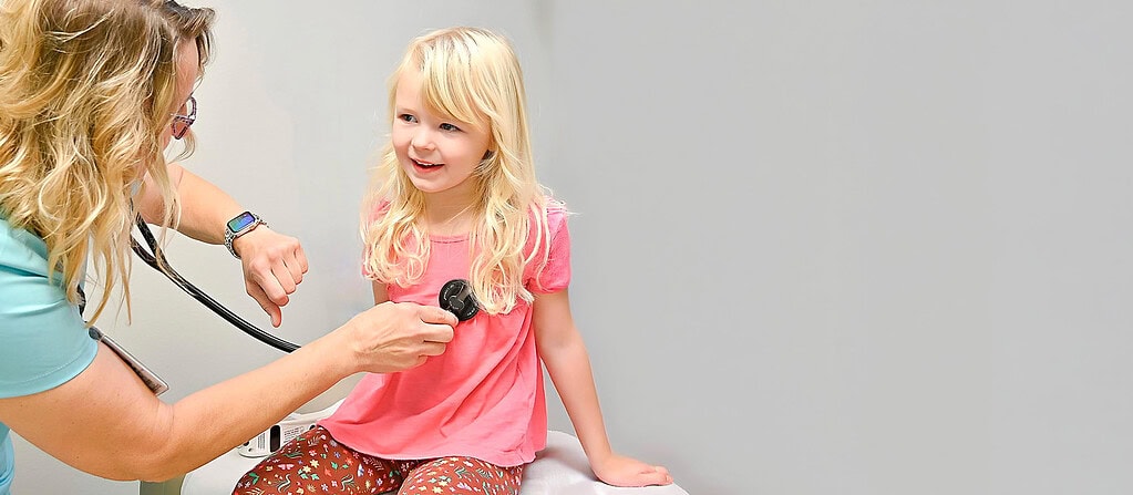 Pediatric doctor examining young girl at Guttenberg Hospital clinic.